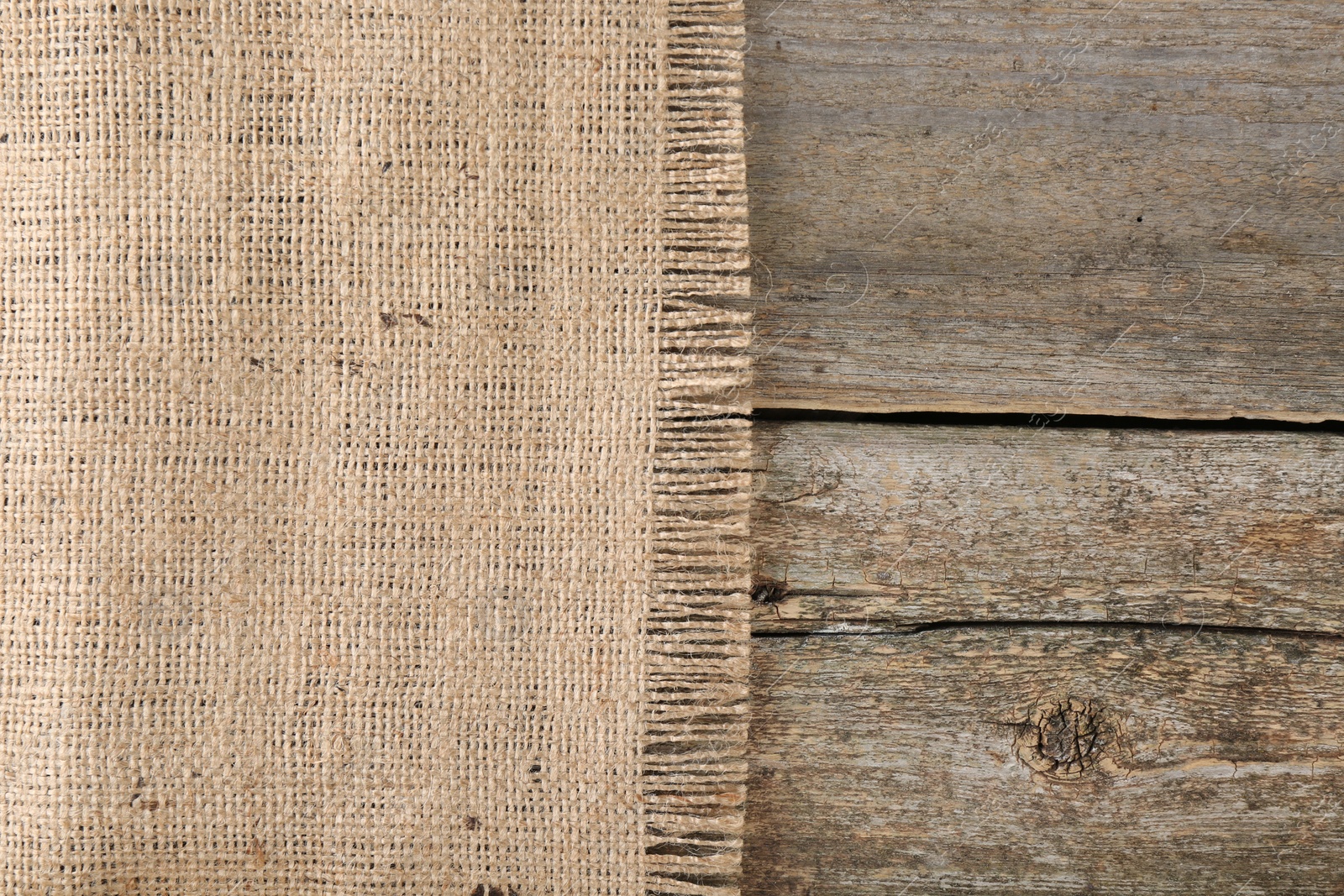 Photo of Piece of burlap fabric on wooden table, top view. Space for text