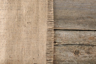 Photo of Piece of burlap fabric on wooden table, top view. Space for text