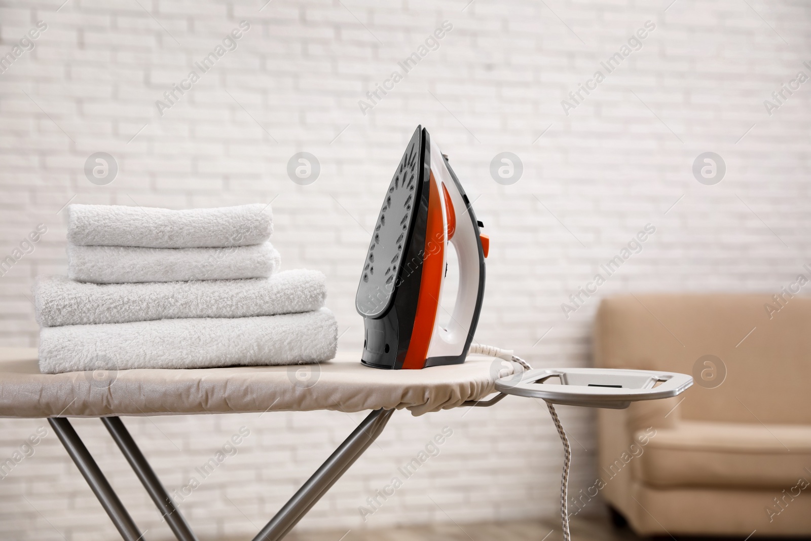 Photo of New modern iron and clean towels on board indoors, space for text. Laundry day