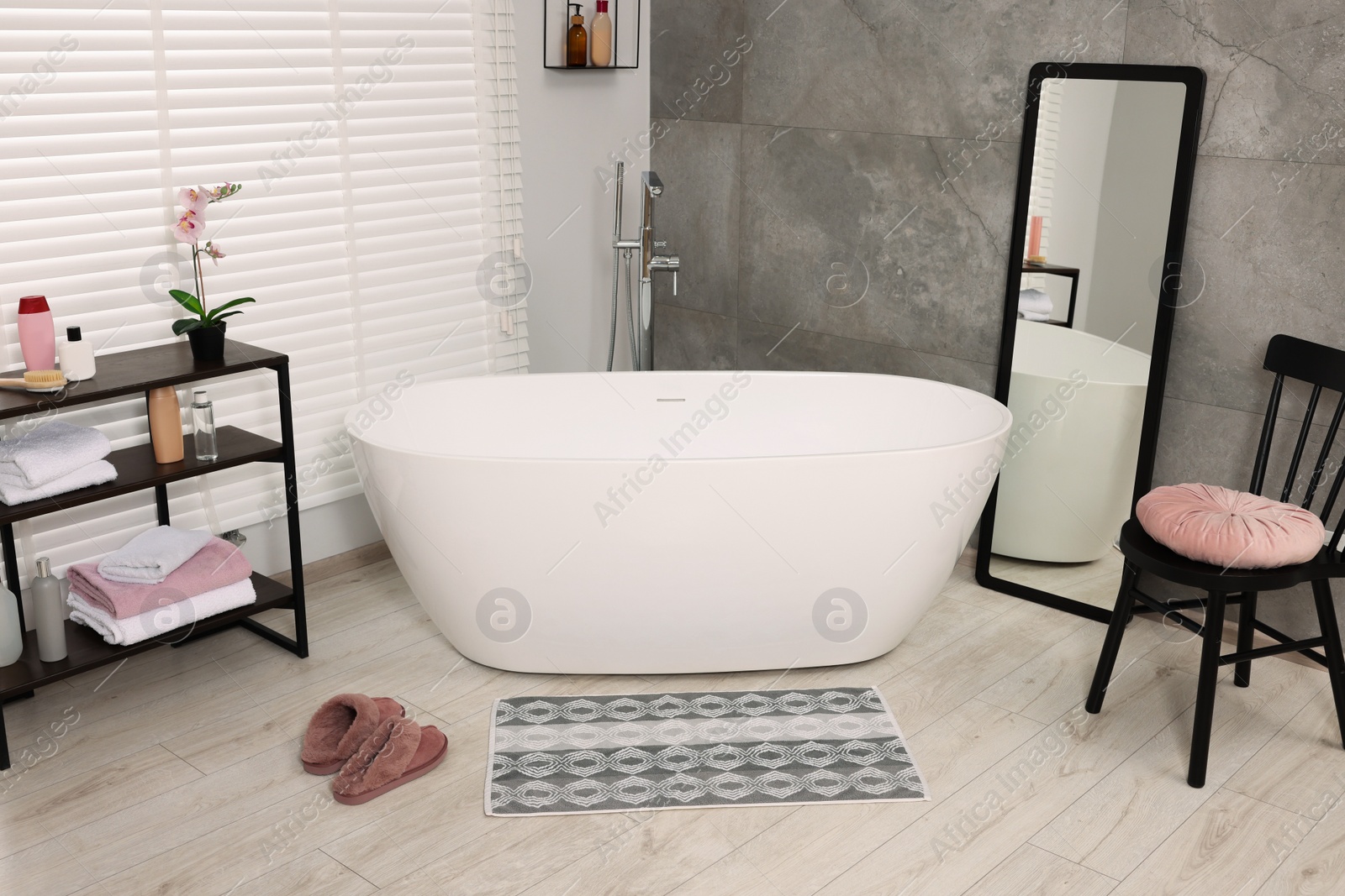 Photo of Stylish bathroom interior with soft bath mat and tub