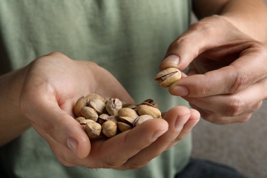 Photo of Woman holding tasty roasted pistachio nuts, closeup