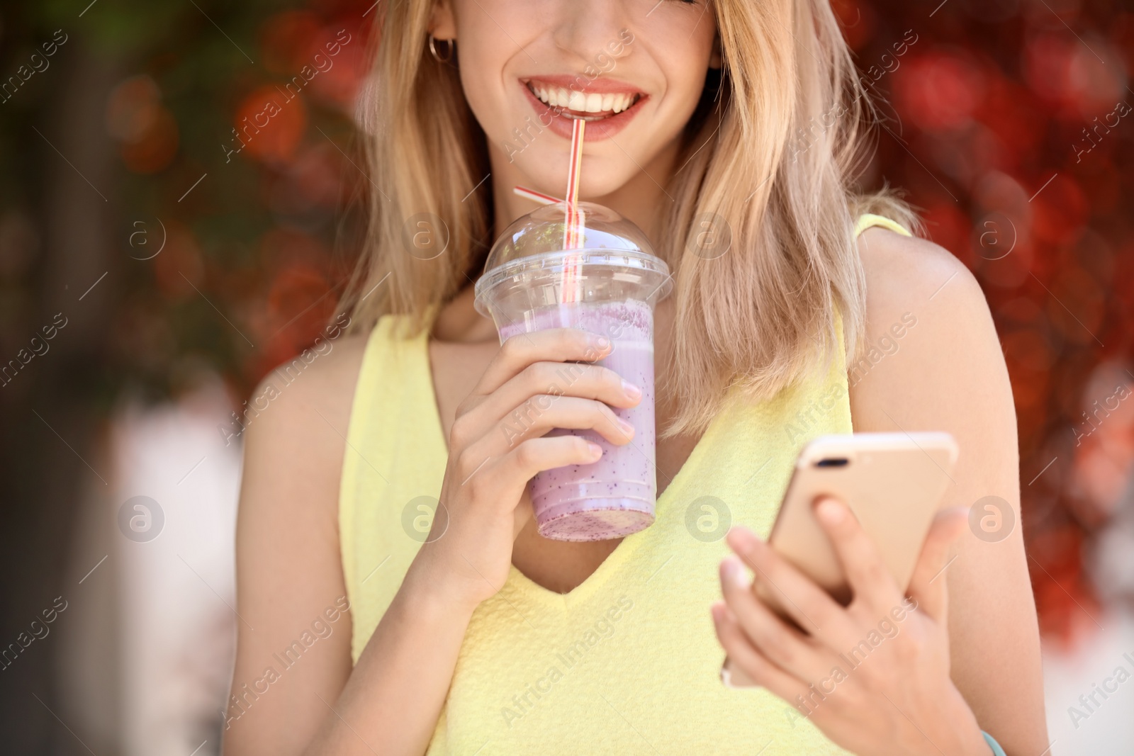 Photo of Young woman with plastic cup of healthy smoothie outdoors