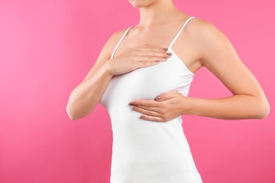 Photo of Woman checking her breast on color background, closeup