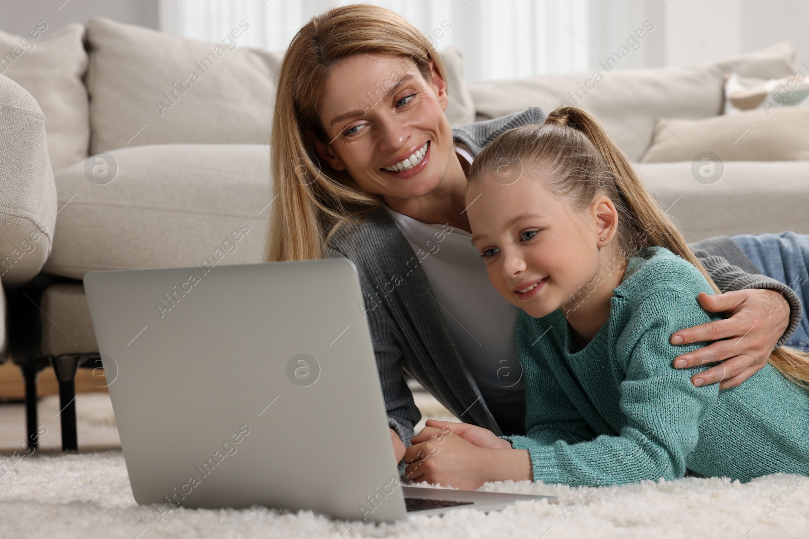 Photo of Happy woman and her daughter with laptop on floor at home