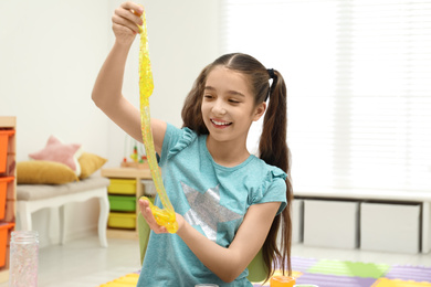 Preteen girl playing with slime in room