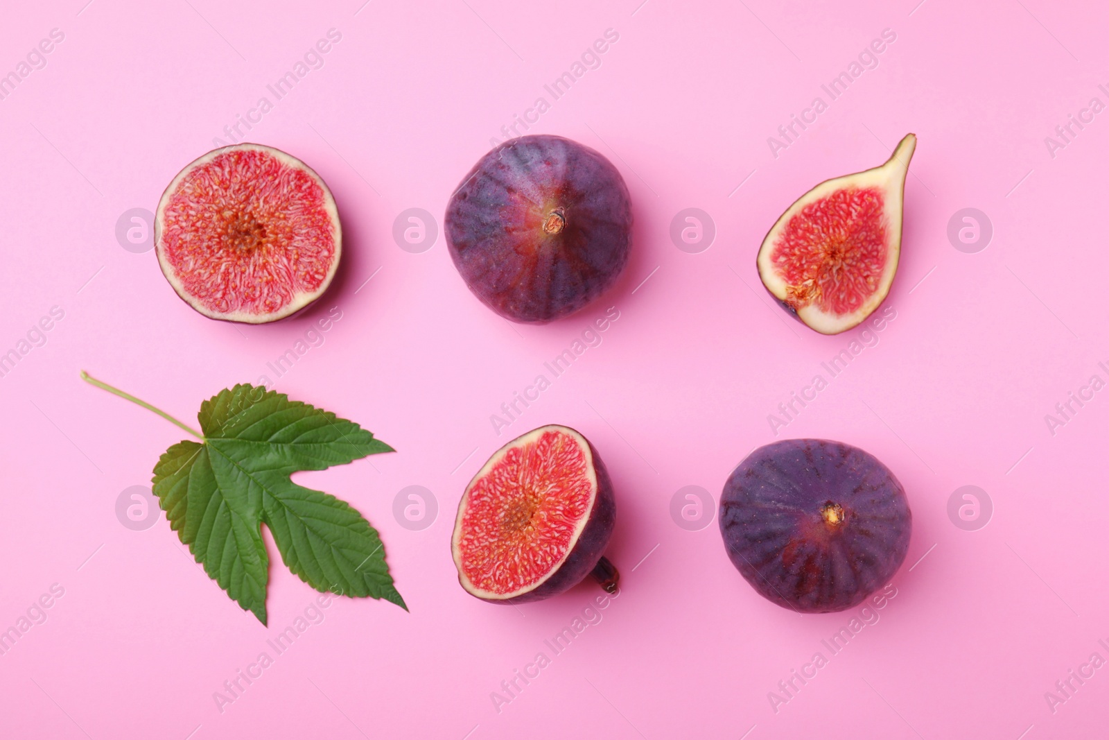 Photo of Fresh ripe figs with green leaf on pink background, flat lay