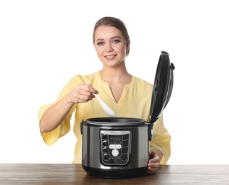 Young woman preparing food with modern multi cooker at table against white background