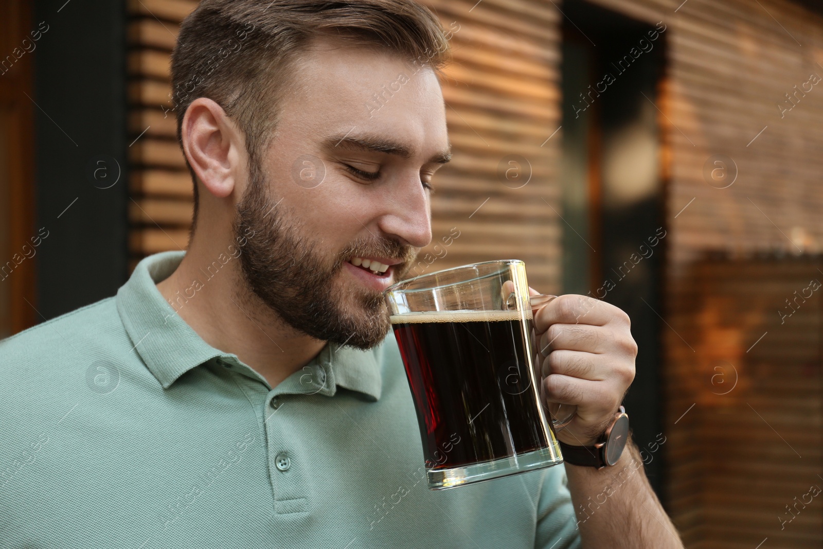 Photo of Handsome man with cold kvass outdoors. Traditional Russian summer drink