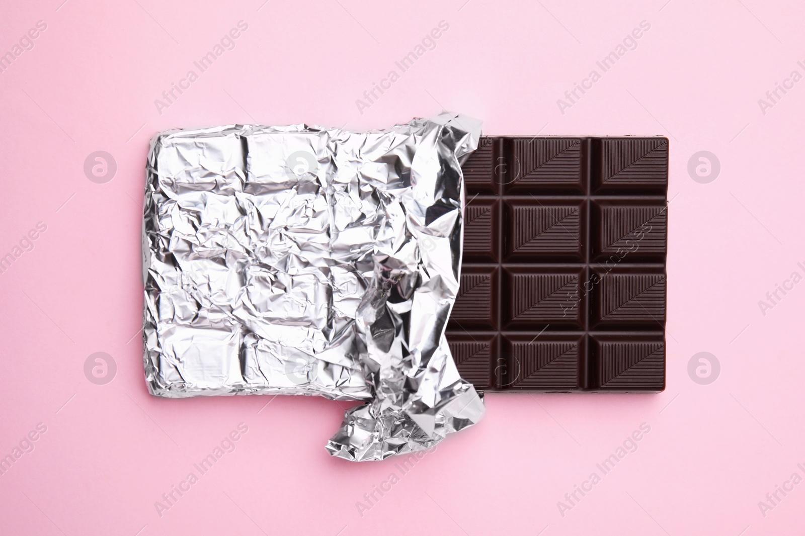 Photo of Tasty chocolate bar on pink background, top view