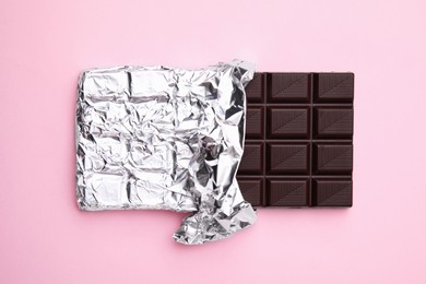 Tasty chocolate bar on pink background, top view