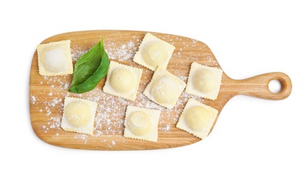 Wooden board with raw ravioli on white background, top view