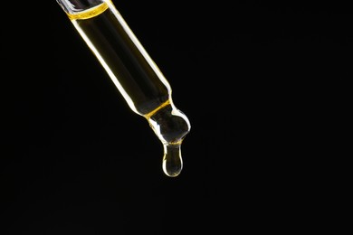 Photo of Dripping tincture from pipette on black background, closeup. Space for text