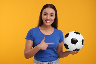 Happy fan showing soccer ball on yellow background