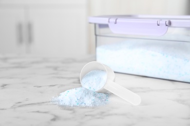 Photo of Measuring scoop with laundry powder near container on table. Space for text