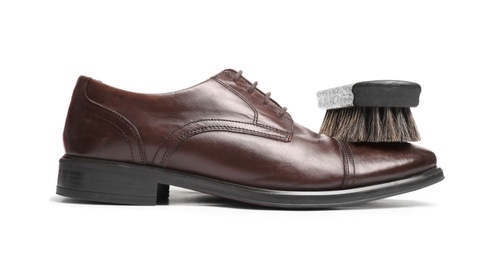 Photo of Stylish men's shoe and cleaning brush on white background