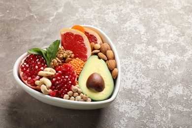 Photo of Bowl with products for heart-healthy diet on color table. Space for text