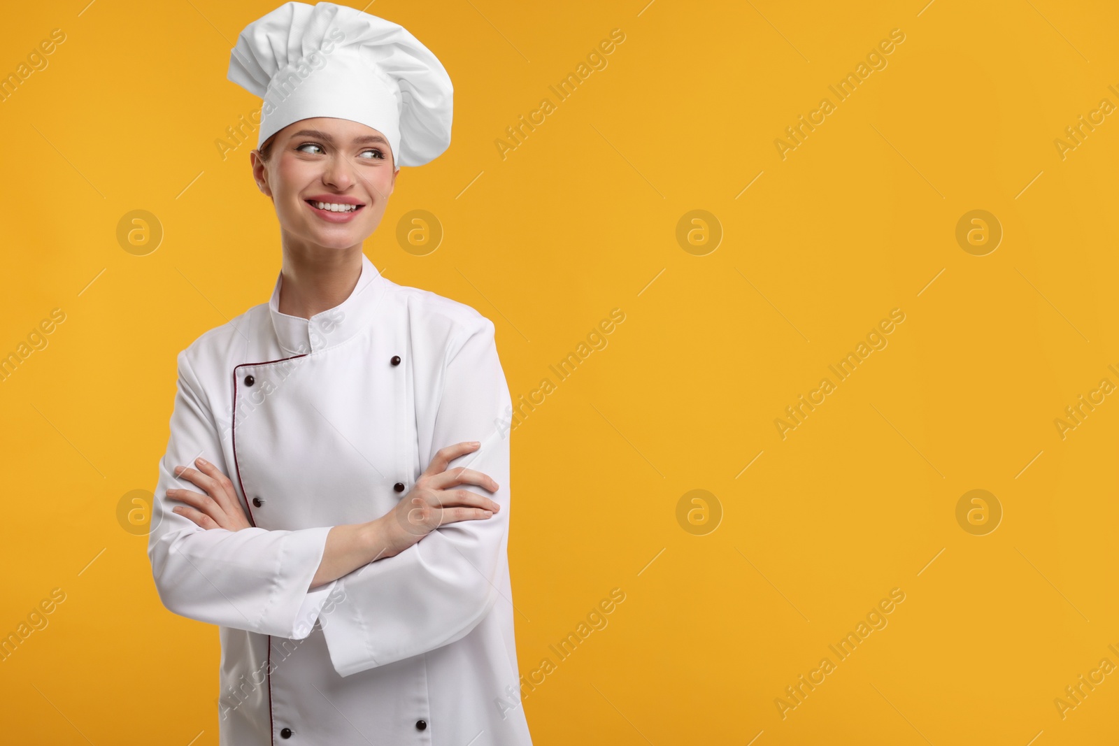 Photo of Happy chef in uniform on orange background, space for text