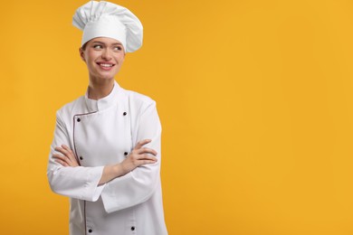 Happy chef in uniform on orange background, space for text