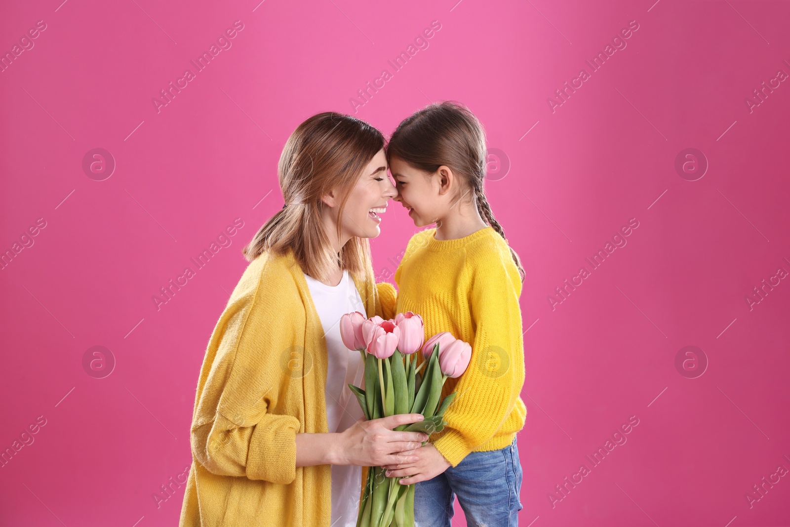 Photo of Happy mother and daughter with flowers on color background. International Women's Day