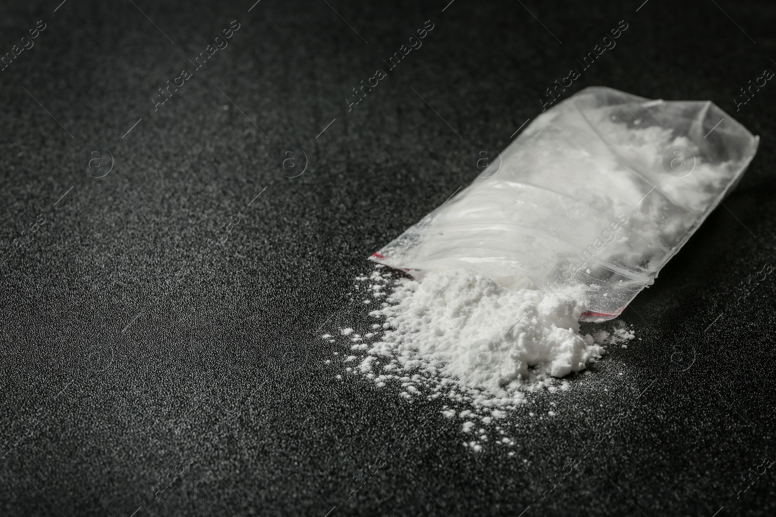 Photo of Cocaine in plastic bag on dark background, closeup. Space for text