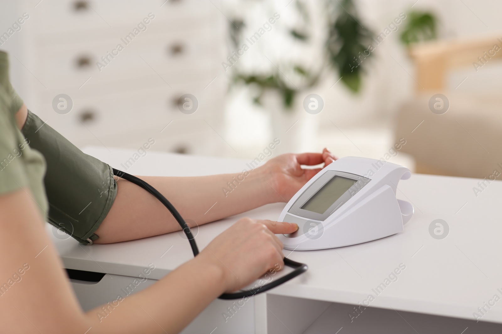 Photo of Woman checking blood pressure at table indoors, closeup