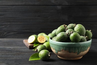 Photo of Fresh green feijoa fruits on black wooden table, space for text