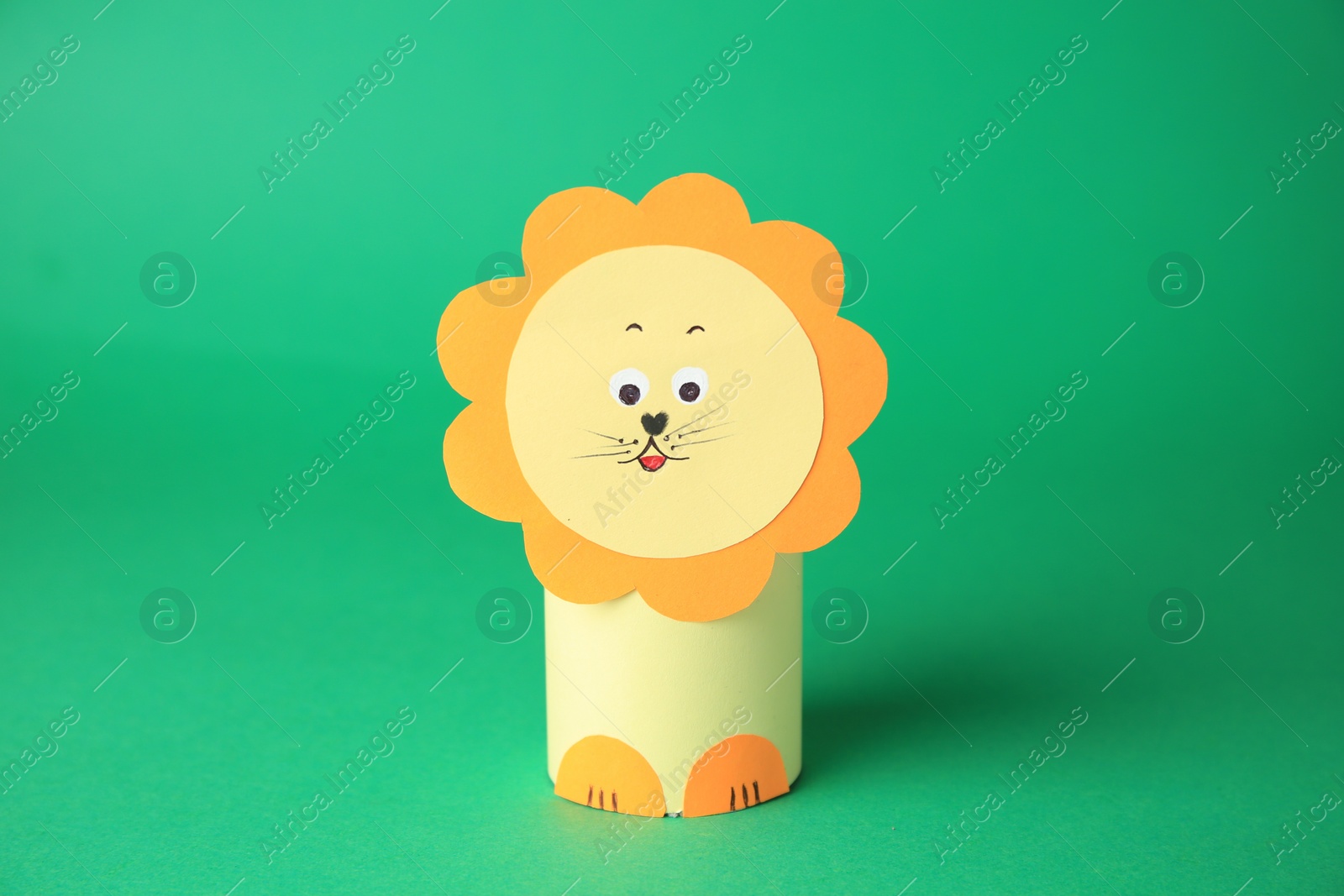 Photo of Toy lion made from toilet paper hub on green background. Children's handmade ideas