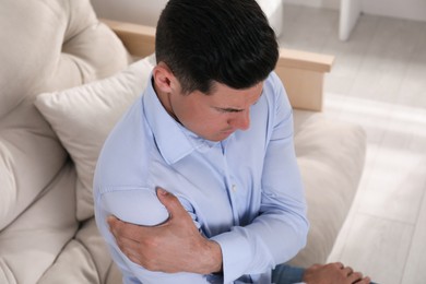 Man suffering from shoulder pain at home, closeup