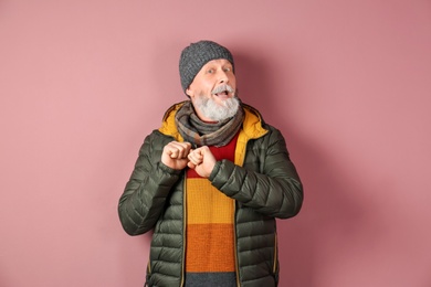 Photo of Mature man in warm clothing on color background. Ready for winter vacation