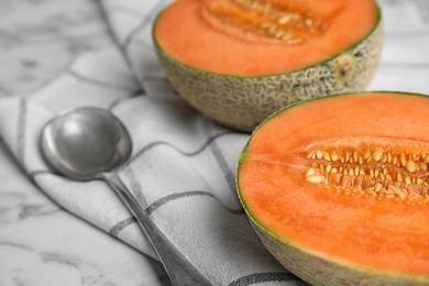 Cut ripe cantaloupe melon and spoon on white marble table, closeup