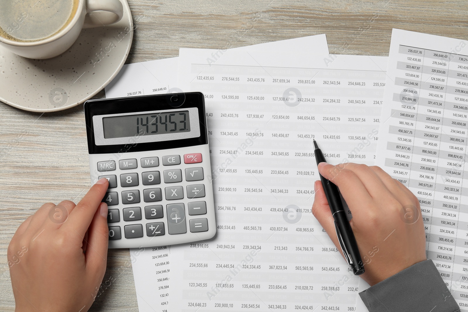 Photo of Woman making calculations on calculator at wooden table, top view