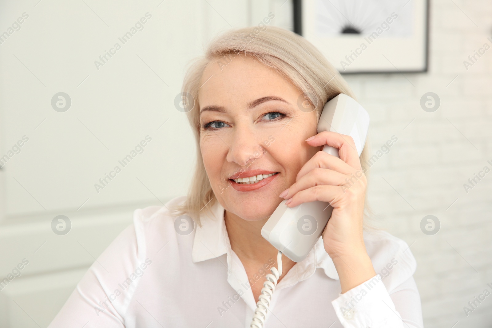 Photo of Mature woman talking on phone at workplace