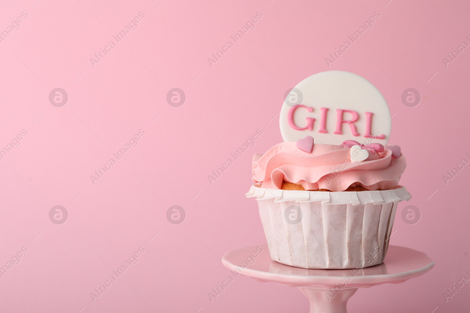 Photo of Baby shower cupcake with Girl topper on pink background, closeup. Space for text