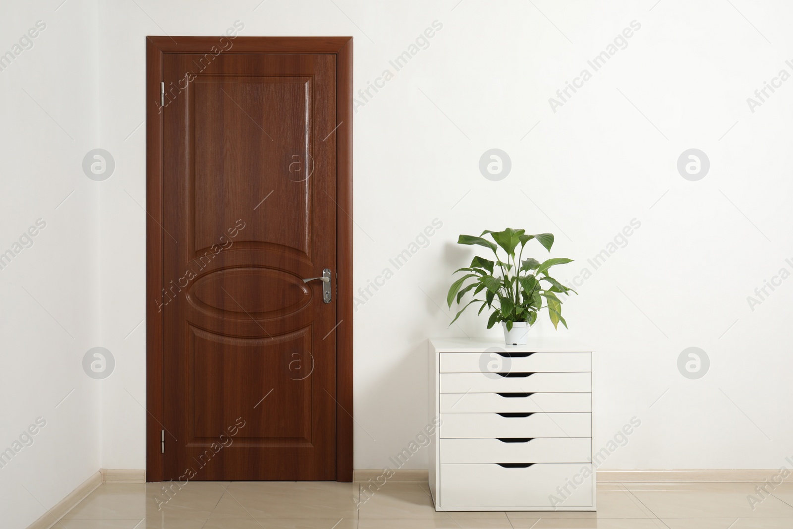 Photo of Modern room interior with small cabinet and closed door. Space for text