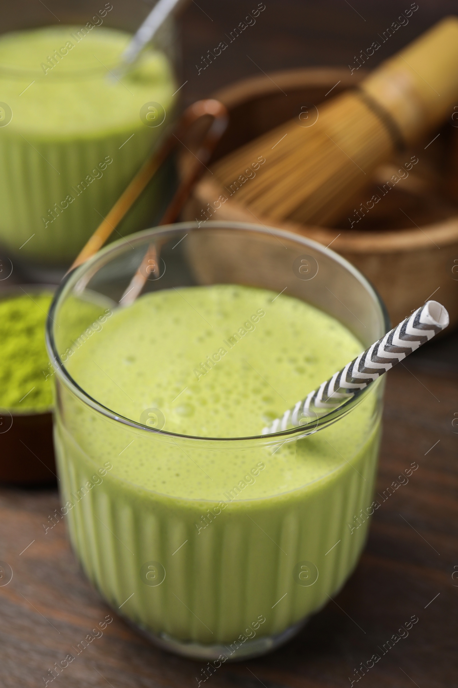 Photo of Glass of tasty matcha smoothie with straw on wooden table, closeup