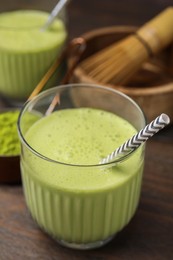 Glass of tasty matcha smoothie with straw on wooden table, closeup