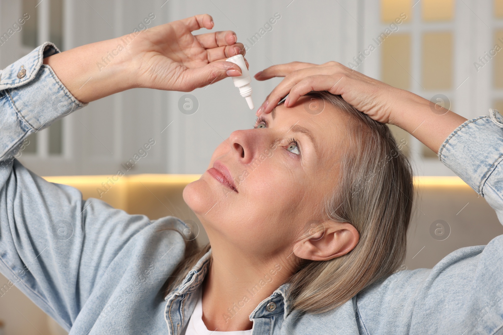 Photo of Woman applying medical eye drops at home