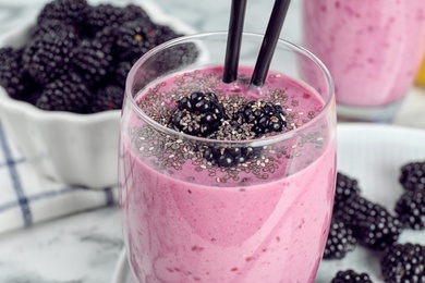 Photo of Delicious blackberry smoothie in glass on marble table, closeup