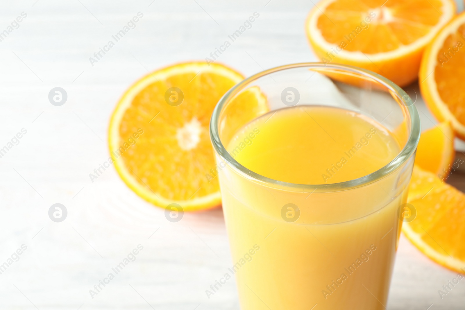 Photo of Glass of orange juice and fresh fruits on white wooden table, closeup