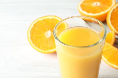 Photo of Glass of orange juice and fresh fruits on white wooden table, closeup