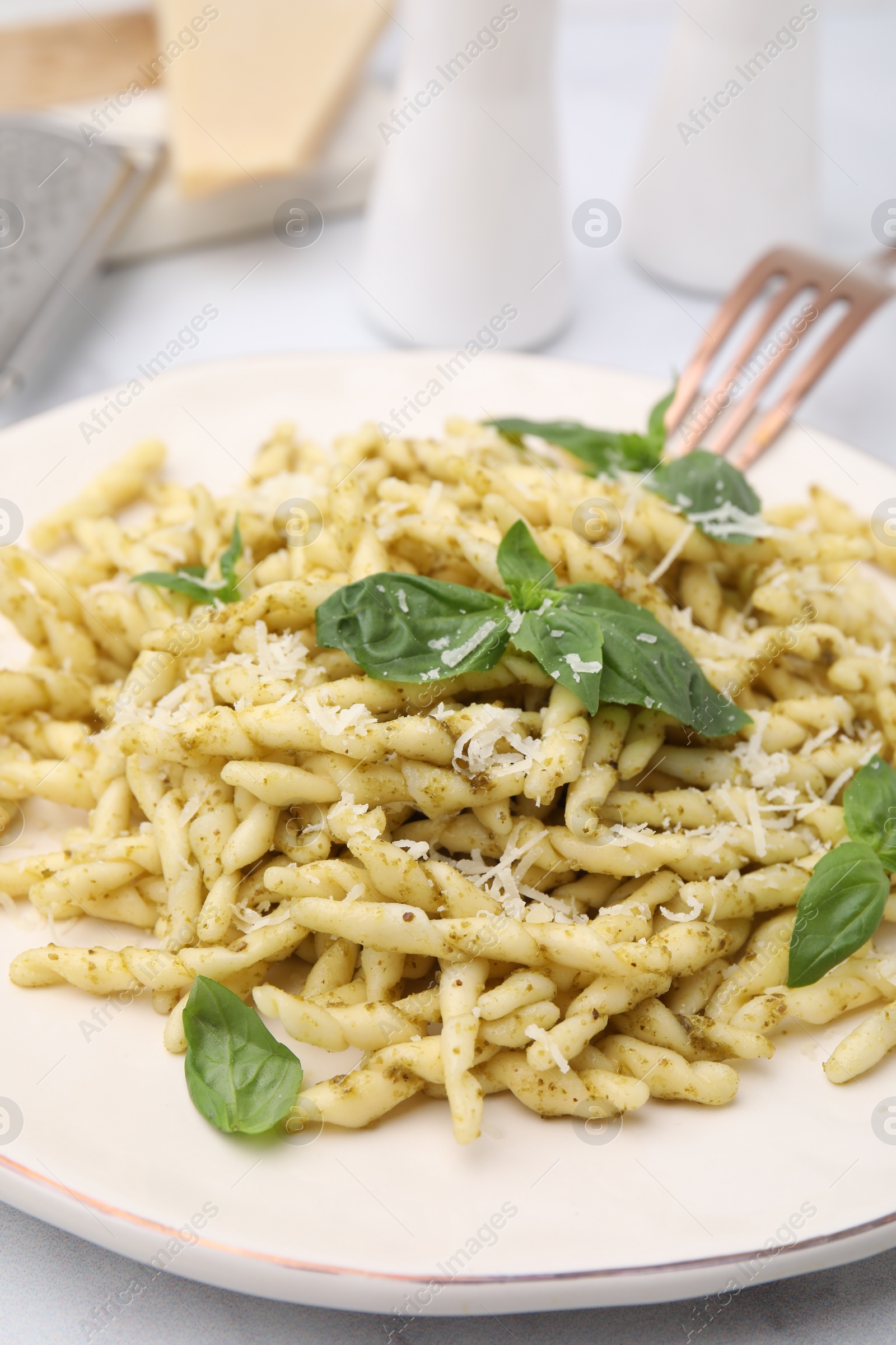 Photo of Plate of delicious trofie pasta with pesto sauce, cheese and basil leaves on table, closeup