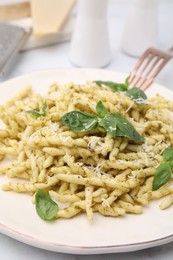 Photo of Plate of delicious trofie pasta with pesto sauce, cheese and basil leaves on table, closeup