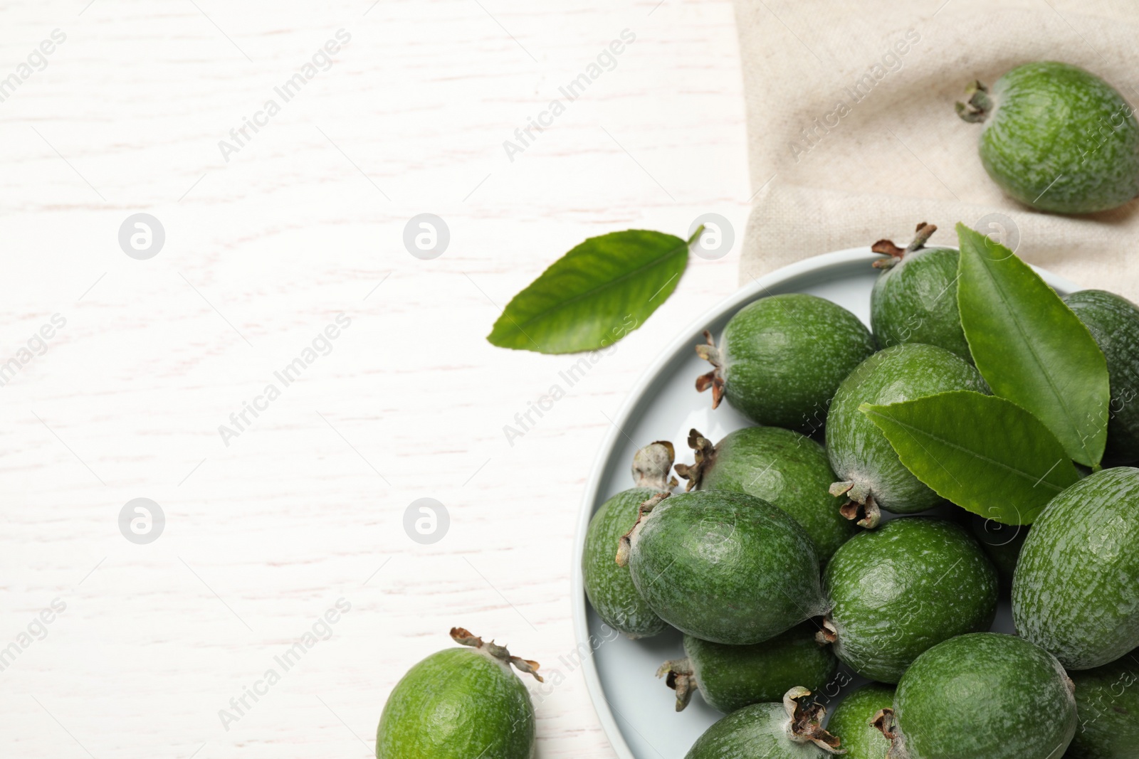 Photo of Flat lay composition with fresh green feijoa fruits on white wooden table, space for text