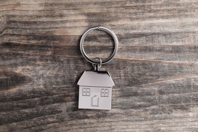 Photo of Metal keychain in shape of house on rustic wooden table, top view