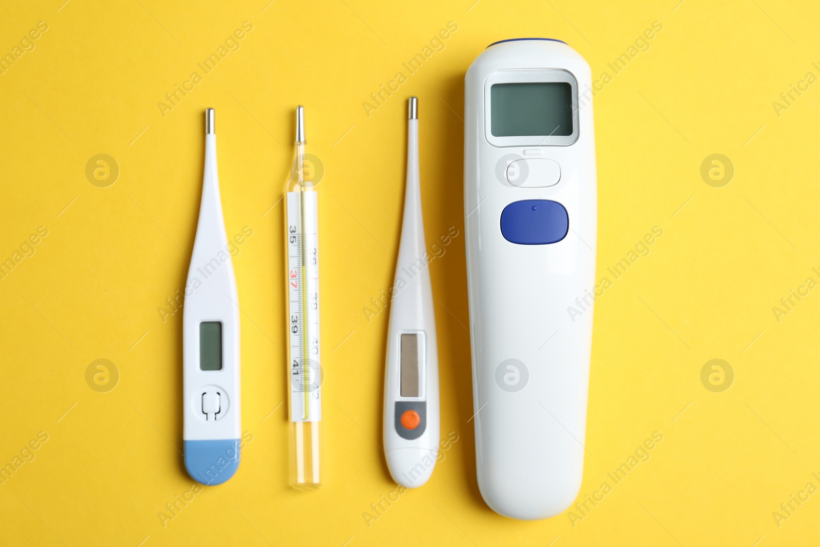 Photo of Different thermometers on yellow background, flat lay