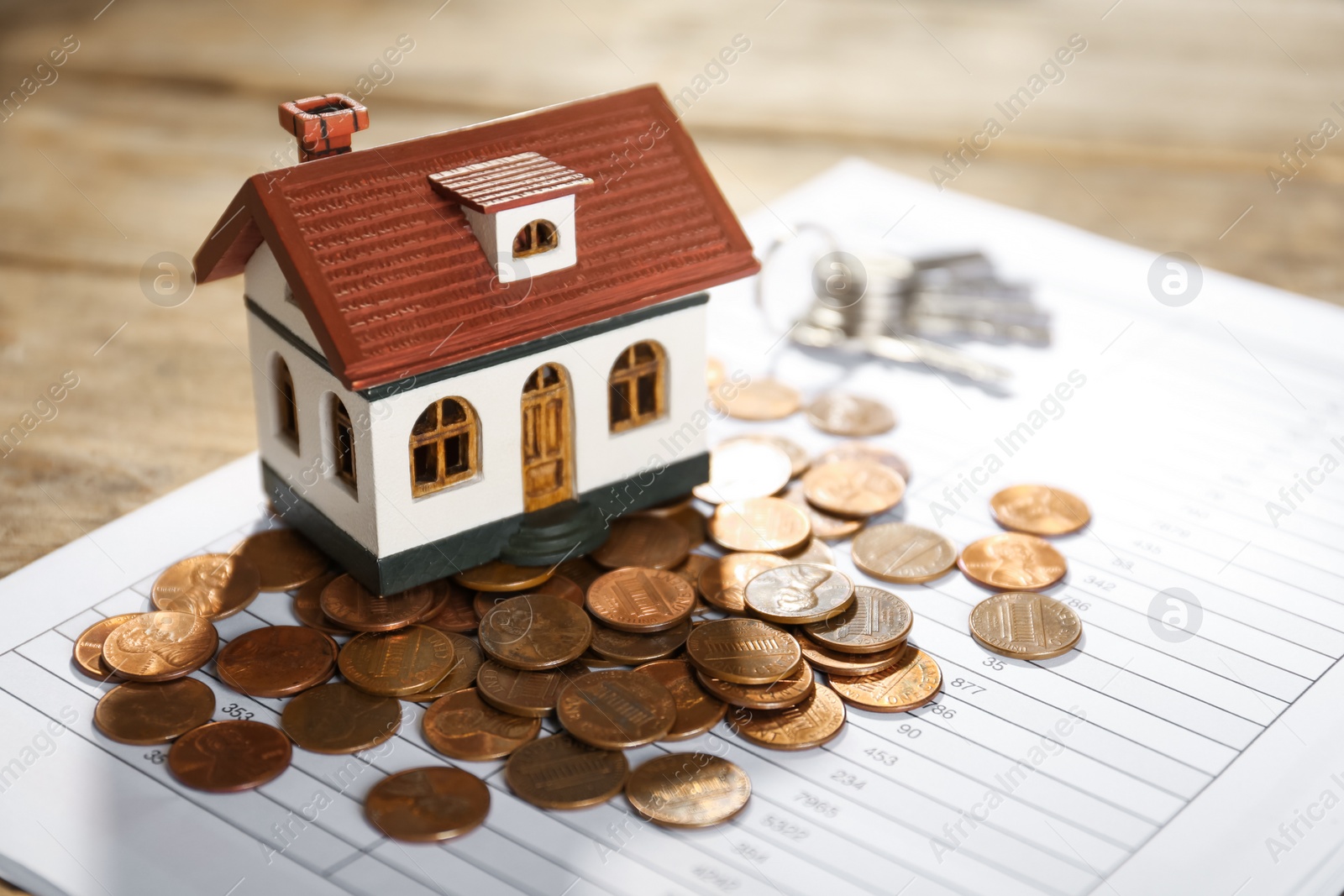 Photo of House model with coins and document on table, closeup. Real estate agent service