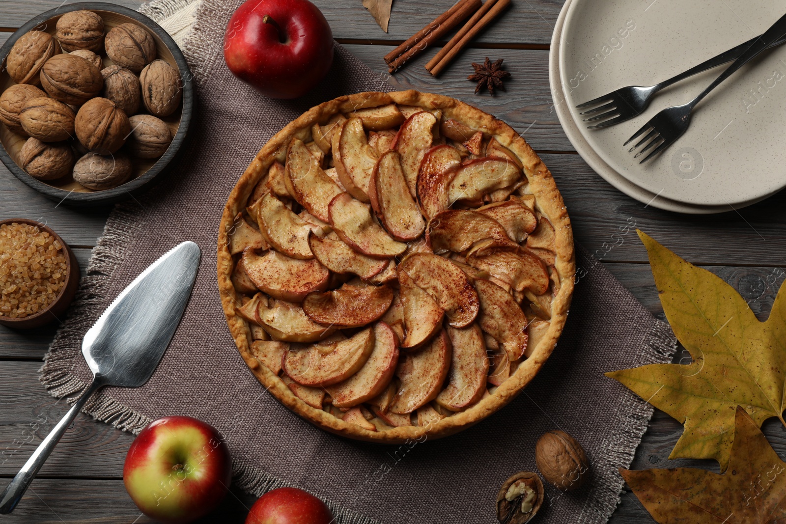 Photo of Delicious apple pie and ingredients on grey wooden table, flat lay