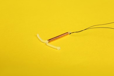 Photo of T-shaped intrauterine birth control device on yellow background
