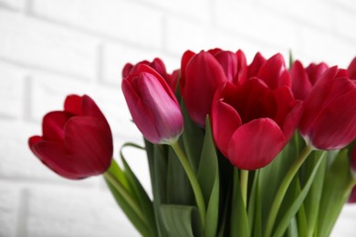 Photo of Bouquet of beautiful tulips near white brick wall, closeup