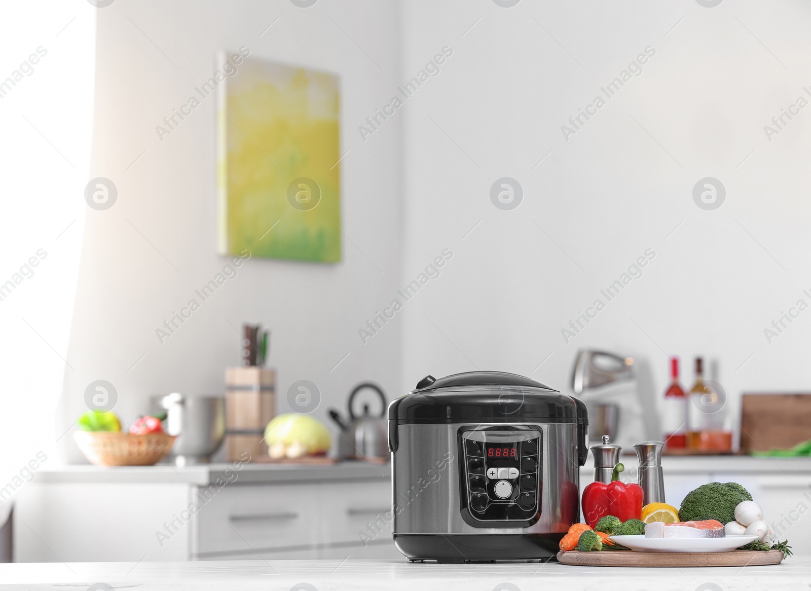 Photo of Modern multi cooker and products on table in kitchen. Space for text